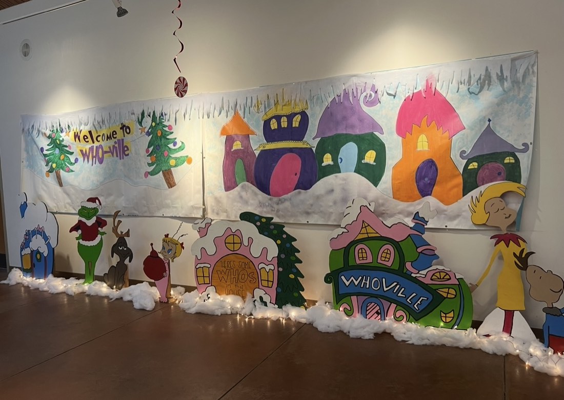A painted Whoville backdrop with cut-out Grinch characters and cotton snow.